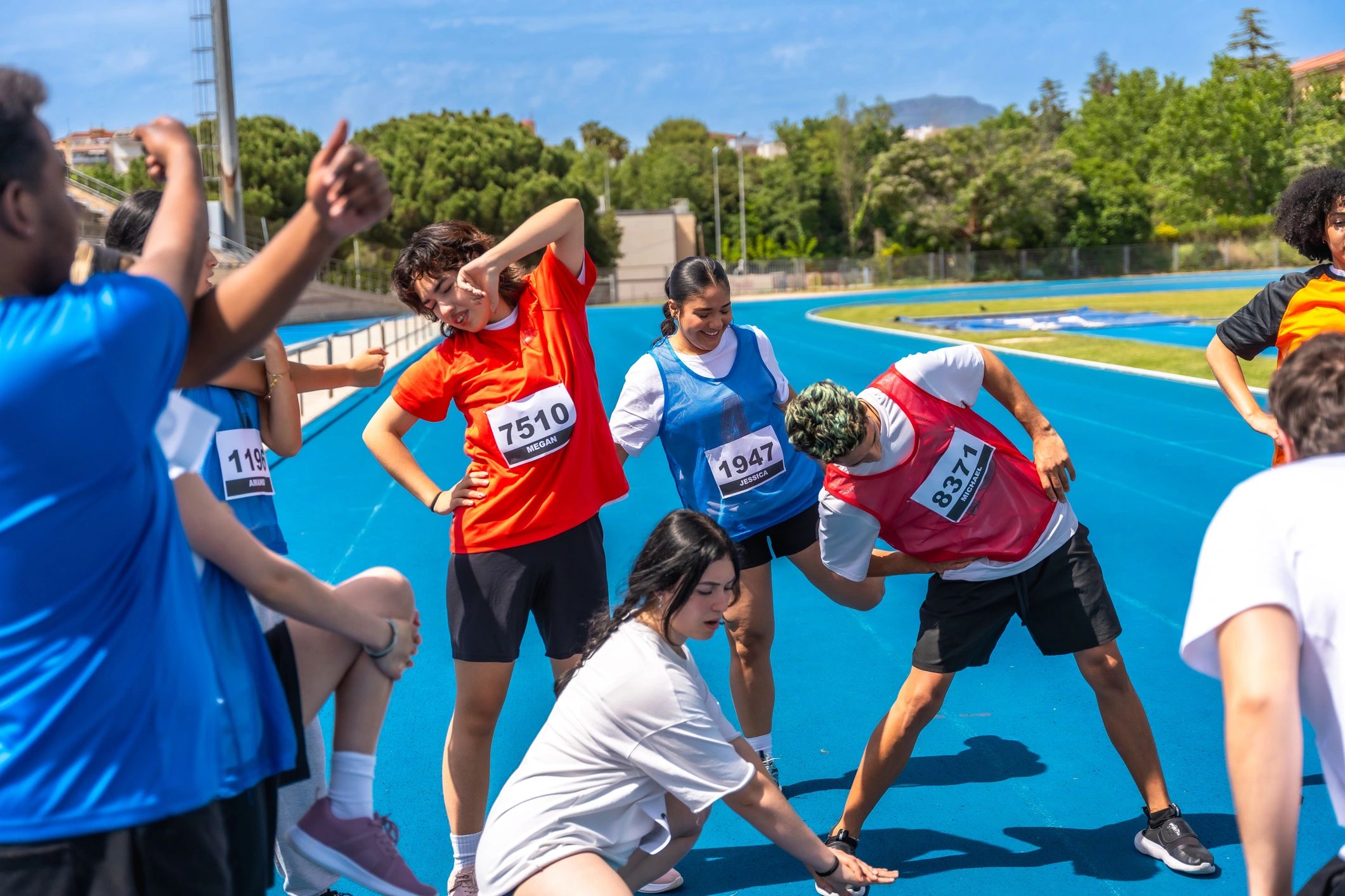 Teen athletes stretching together on a running track